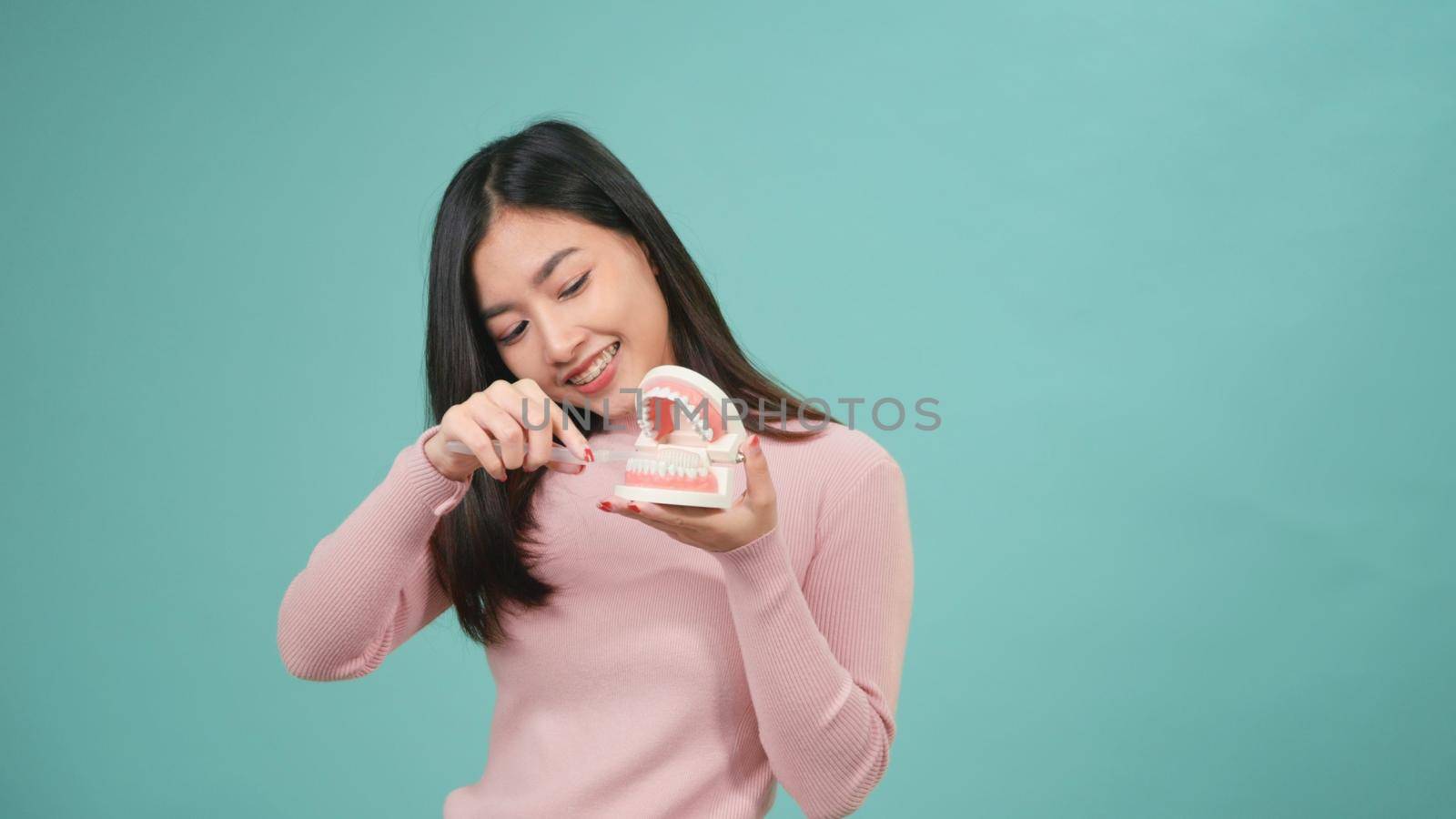 woman smile showing model how to clean the teeth with toothbrush by Sorapop