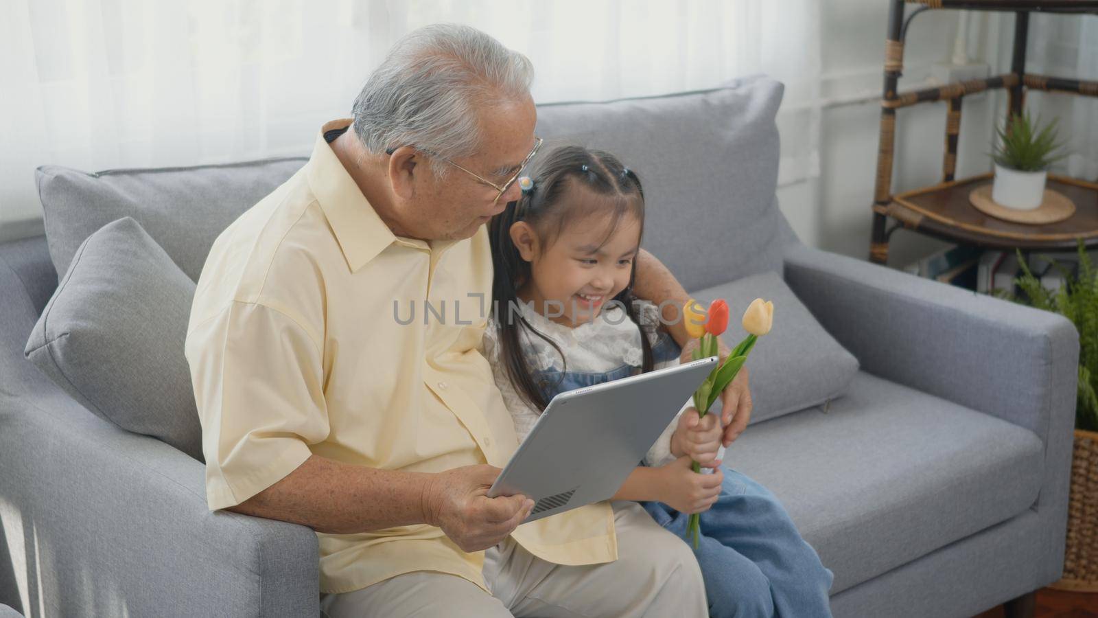 old man looking to tablet computer and granddaughter come visitor at home by Sorapop
