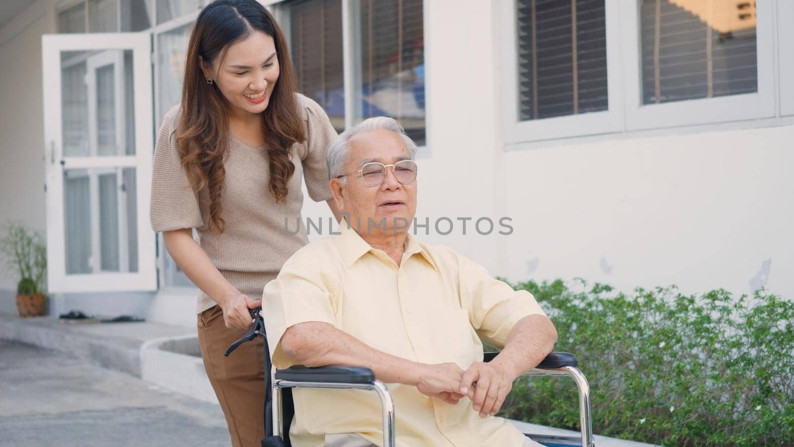 Disabled senior man on wheelchair with daughter in park by Sorapop
