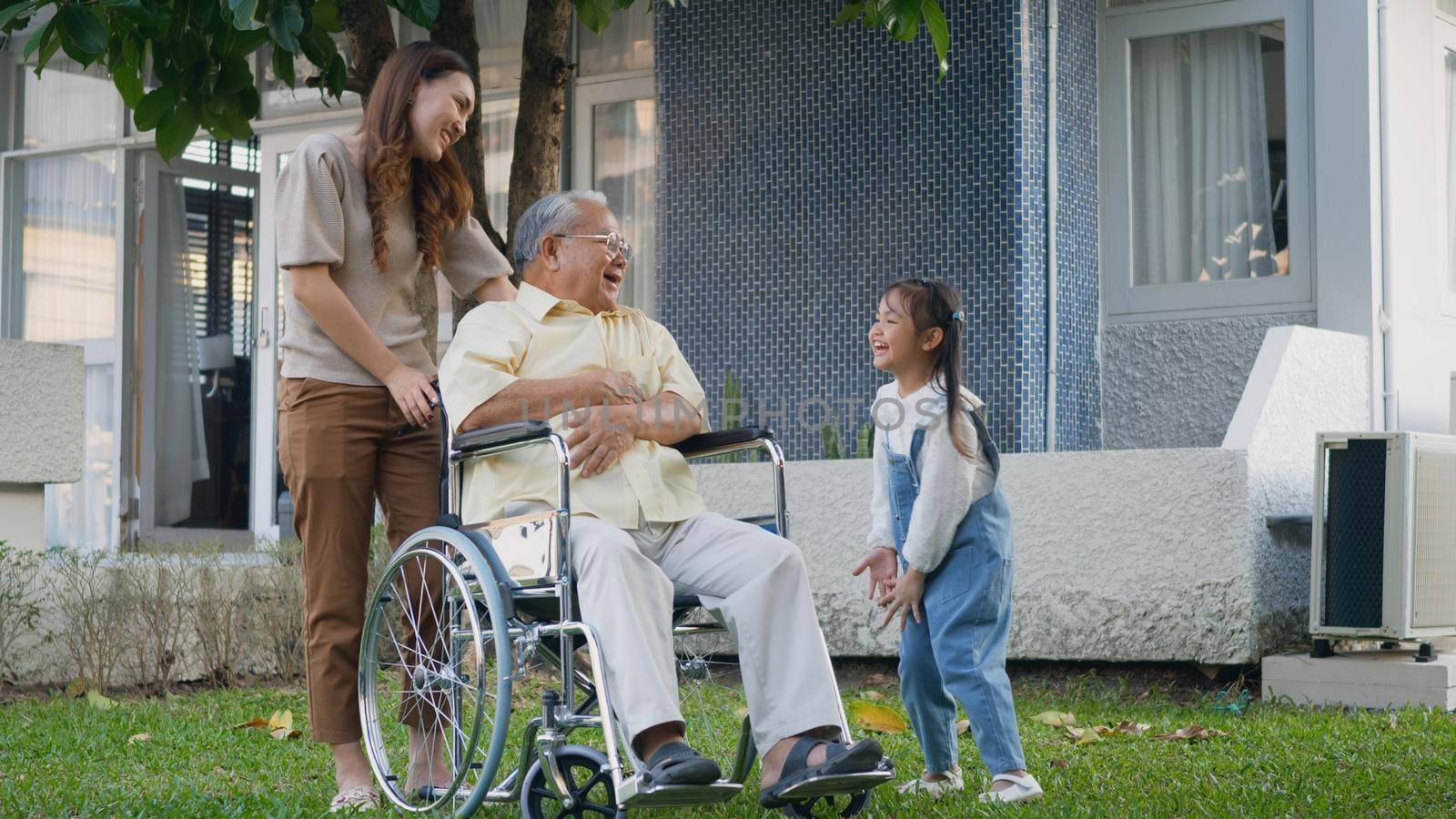 Disabled senior grandpa on wheelchair with grandchild and mother in park by Sorapop