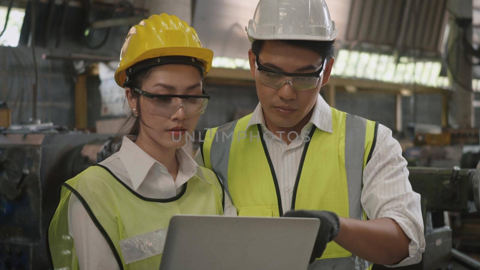 mechanical engineer woman and operation man wearing uniform hardhat and goggles safety working on workshop metal lathe by Sorapop