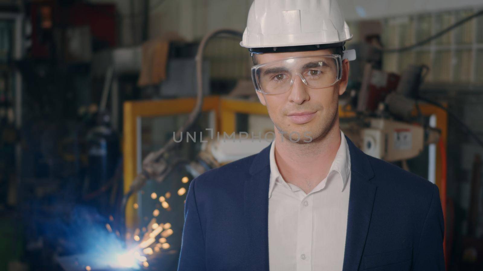 Professional confident engineer businessman in suits safety hats, goggles smile look at camera stand in heavy industrial facility manufacturing with steel welding from with fire spark