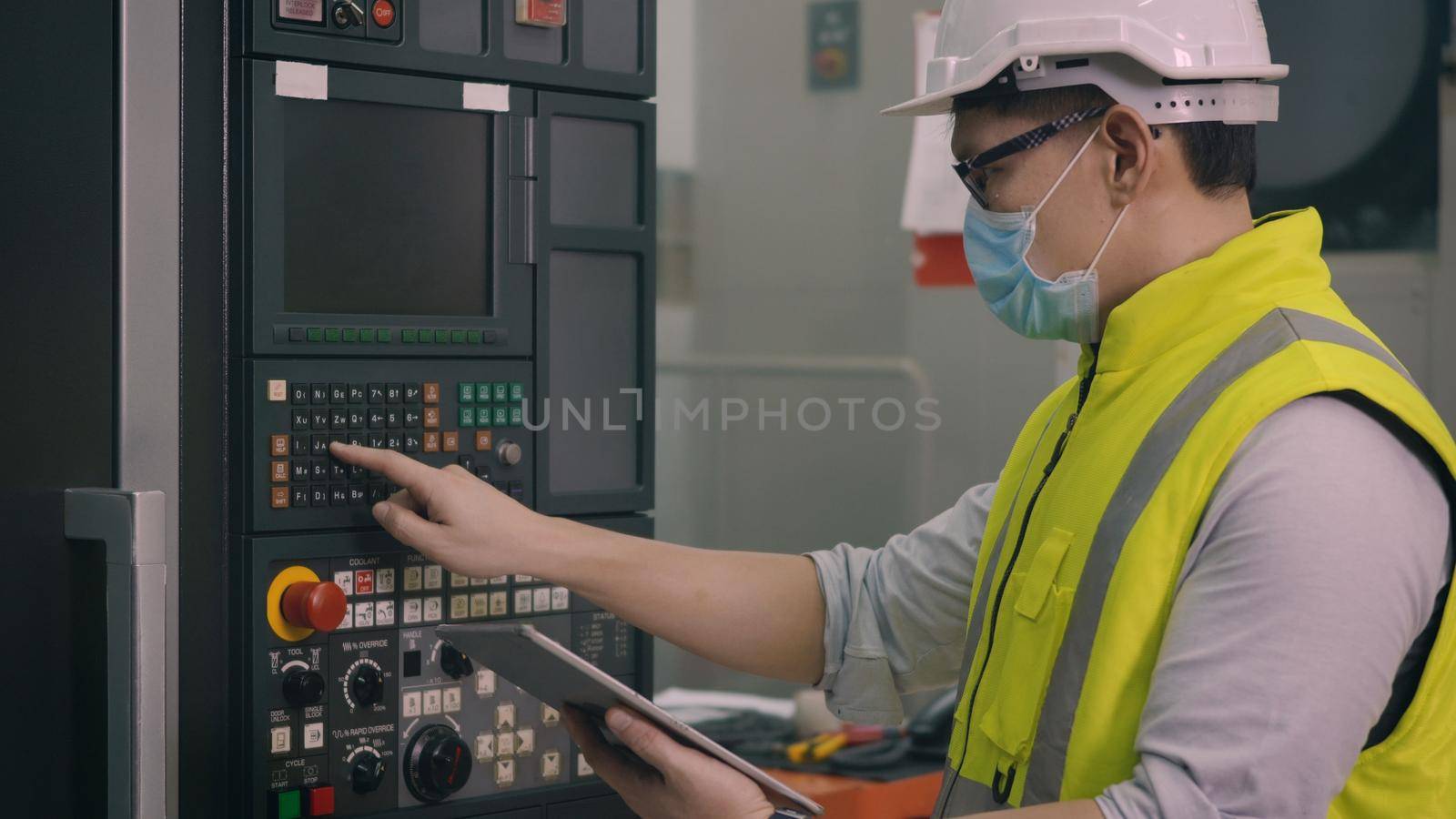 Asian factory worker man operating automated programming CNC milling control machine industry center at tool workshop manufacturing