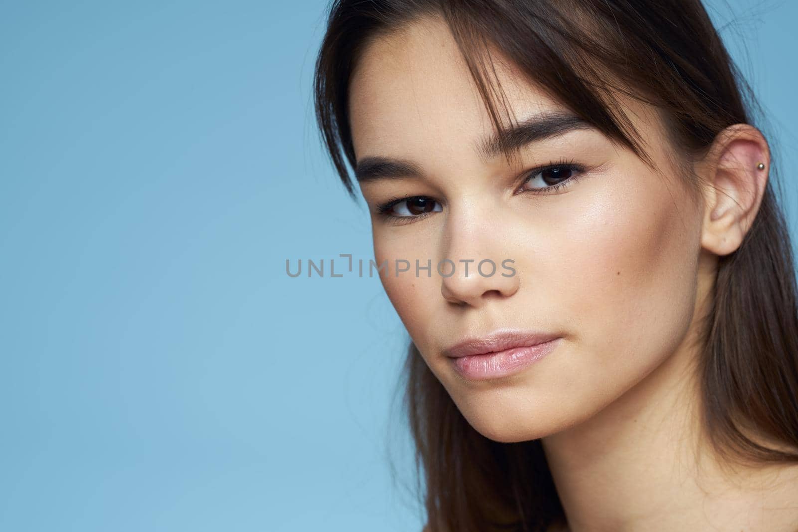 Pretty woman naked shoulders hair care close-up bank blue background. High quality photo