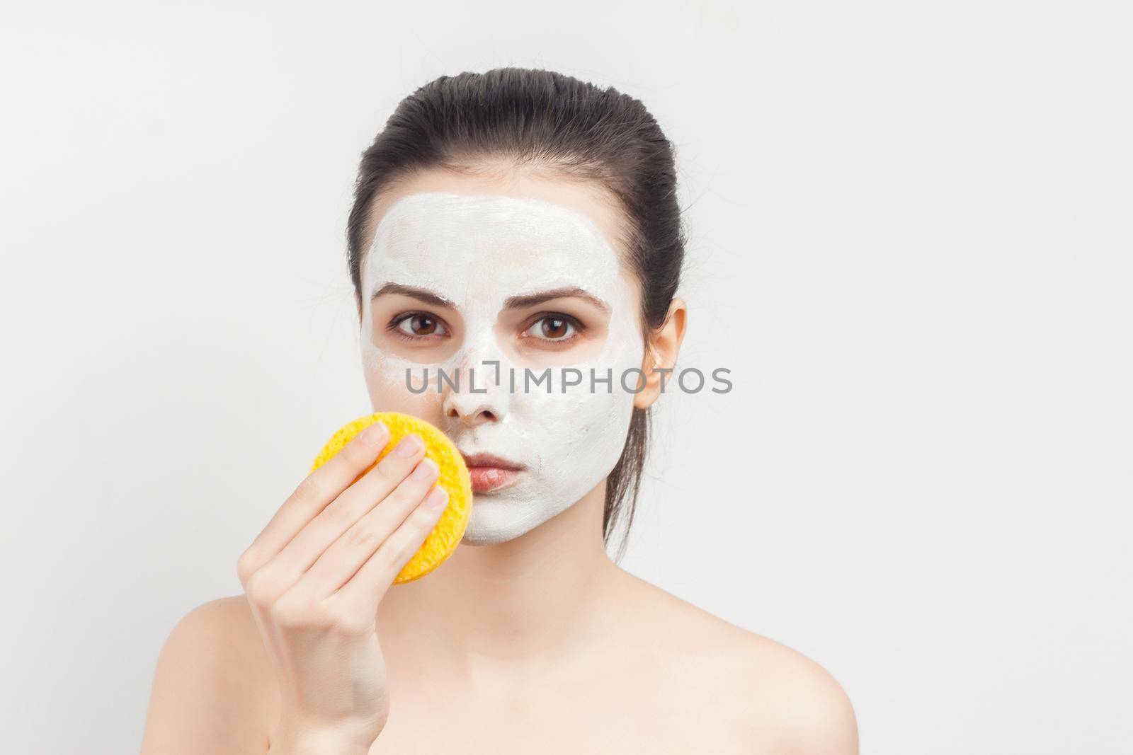 brunette naked shoulders face mask hand sponge. High quality photo