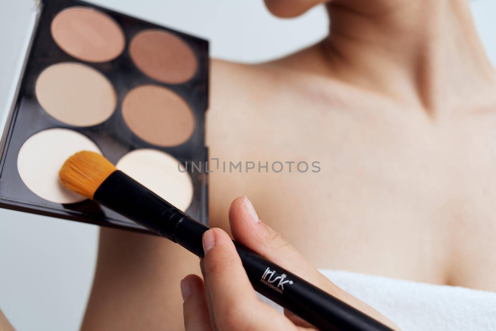 Pretty woman with naked shoulders applying makeup on face lifestyle. High quality photo