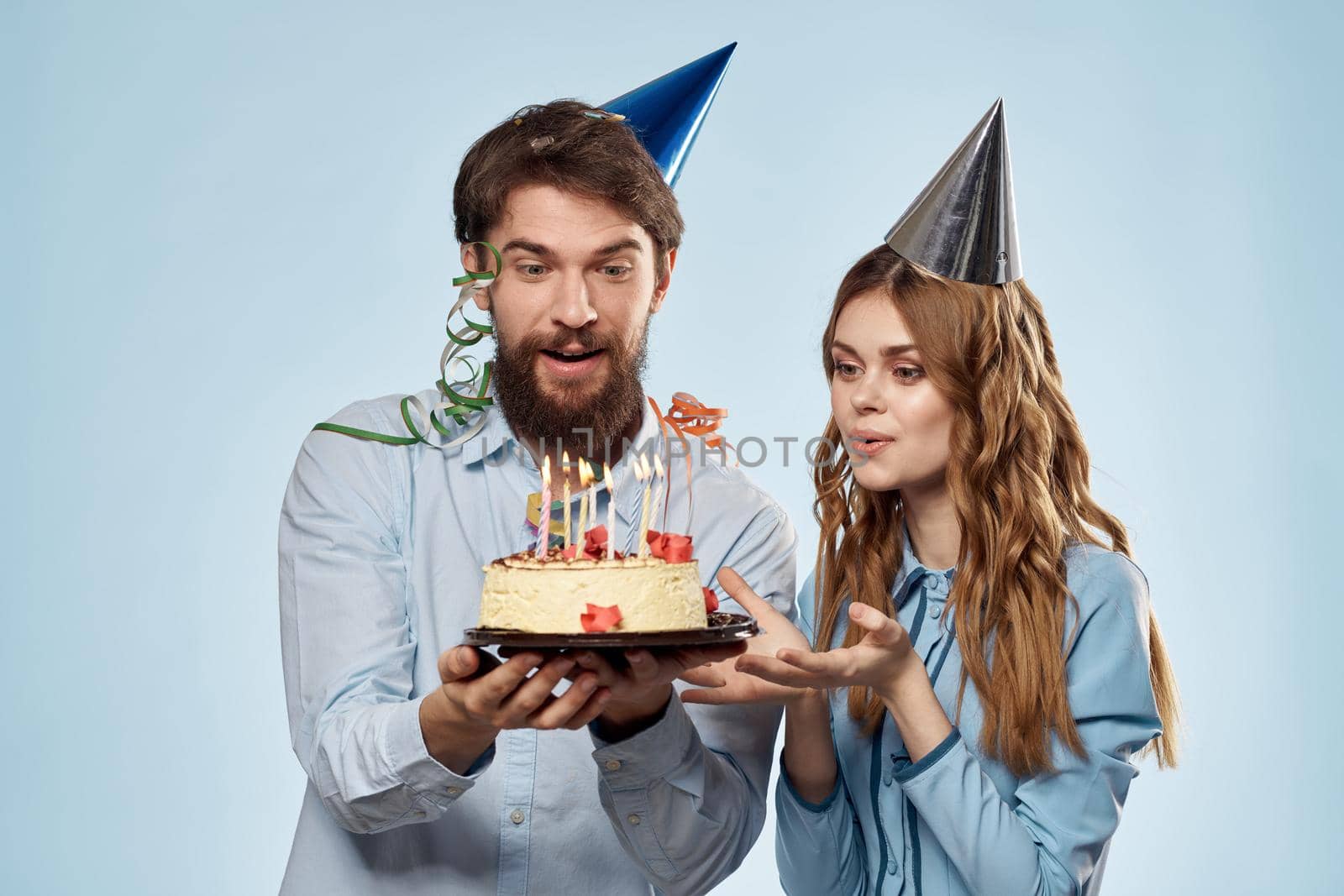 Birthday man woman in party hats on a blue background and cake with candles. High quality photo