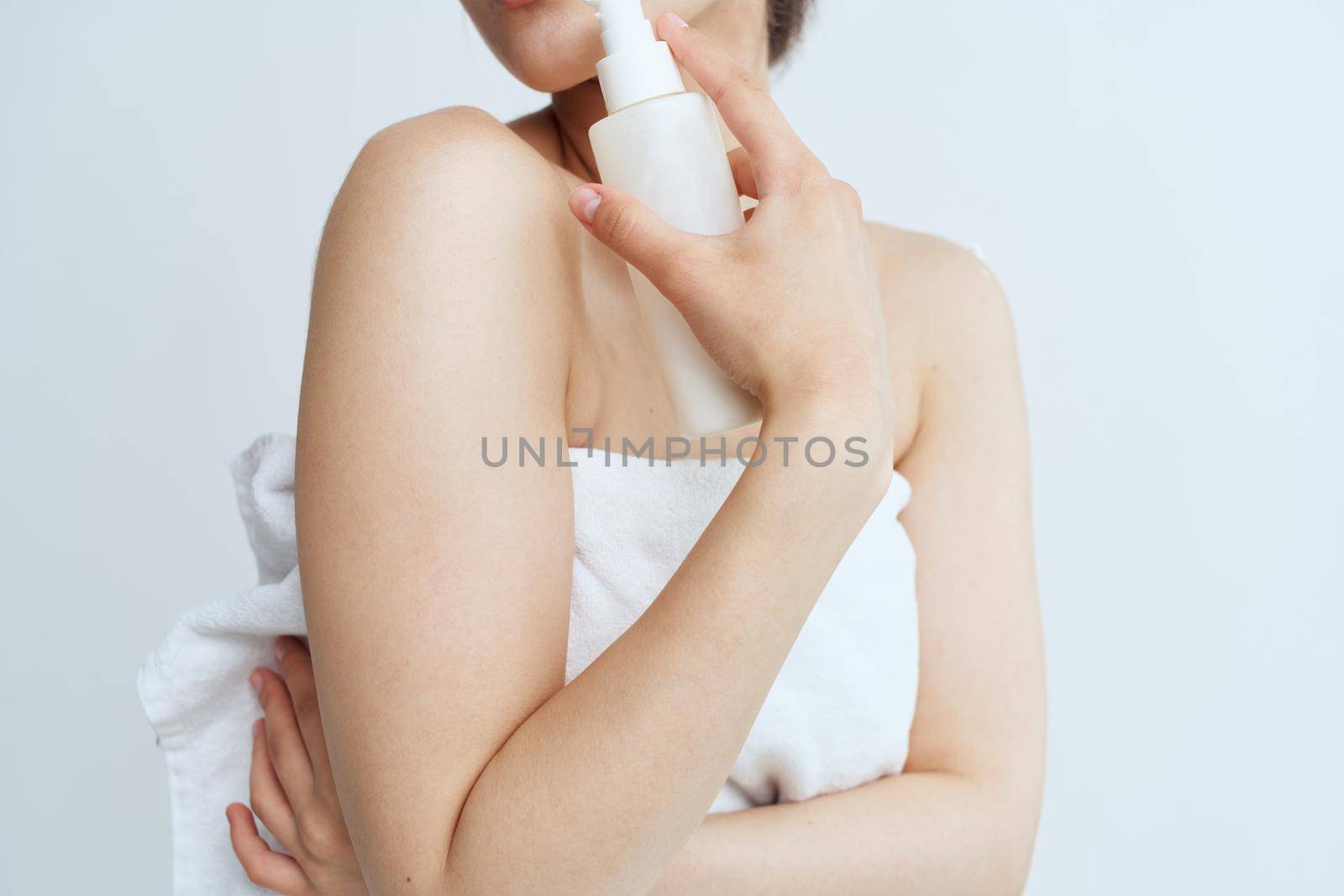 Pretty woman in white towel naked shoulders lotion clean skin hygiene. High quality photo