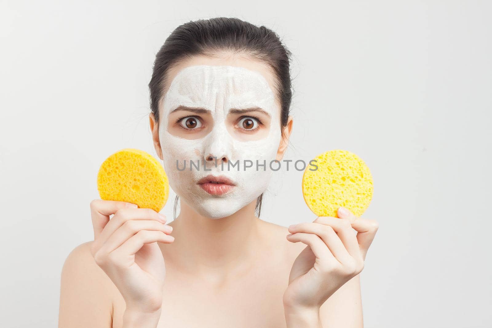 woman with bare shoulders wipes a mask on her face with sponges. High quality photo