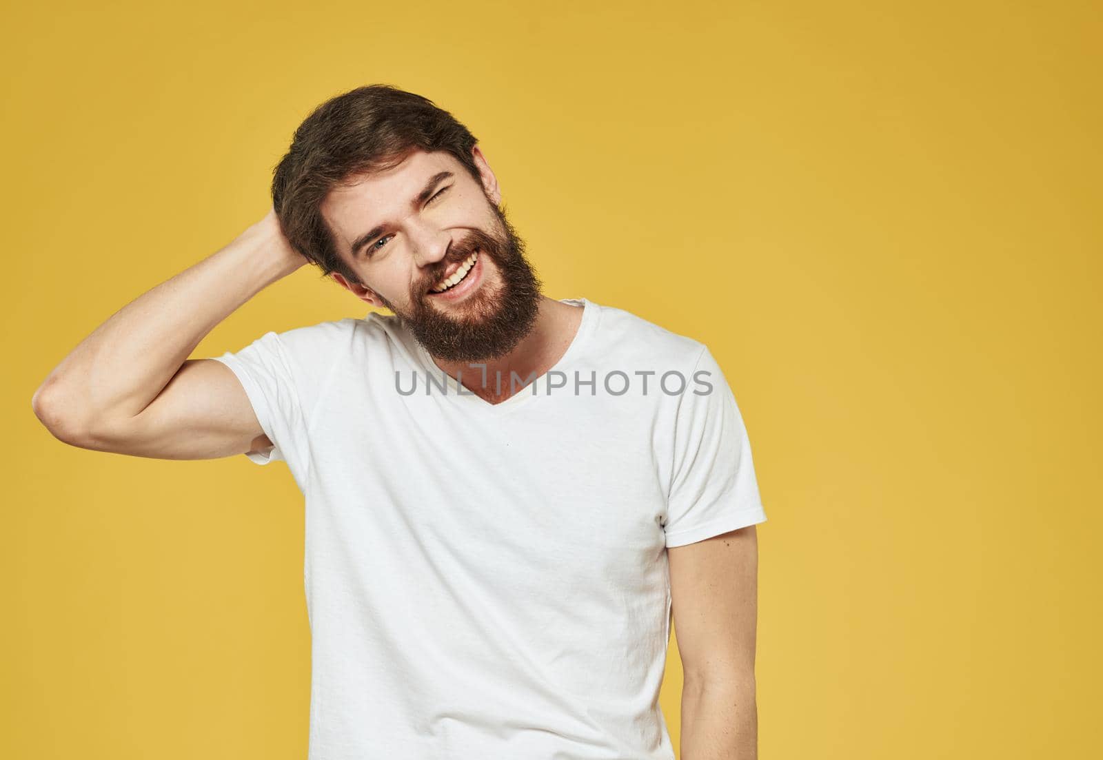 A man in a white T-shirt gestures with his hands on a yellow background Copy Space. High quality photo