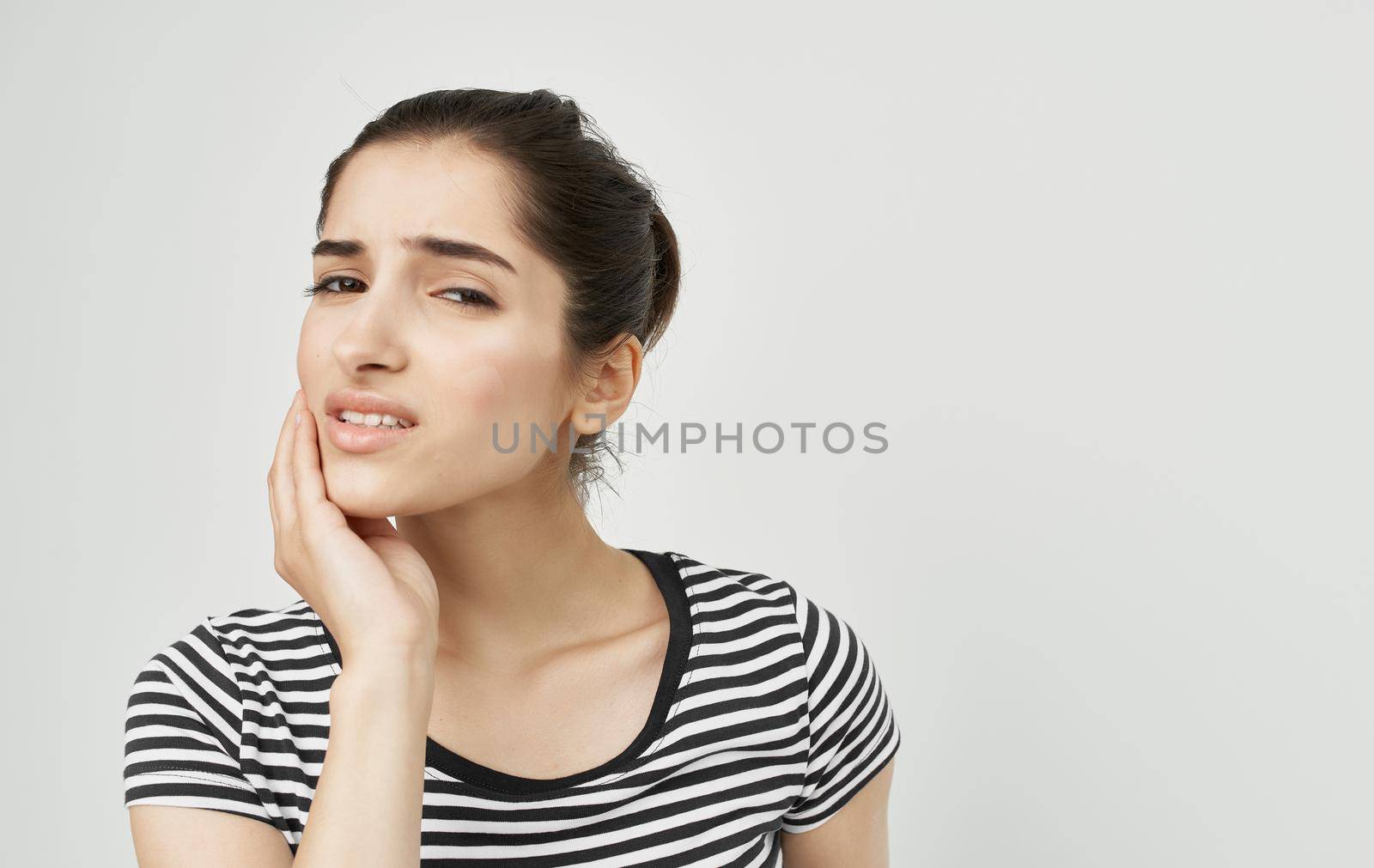 woman in striped t-shirt holding face dental problems pain discontent. High quality photo