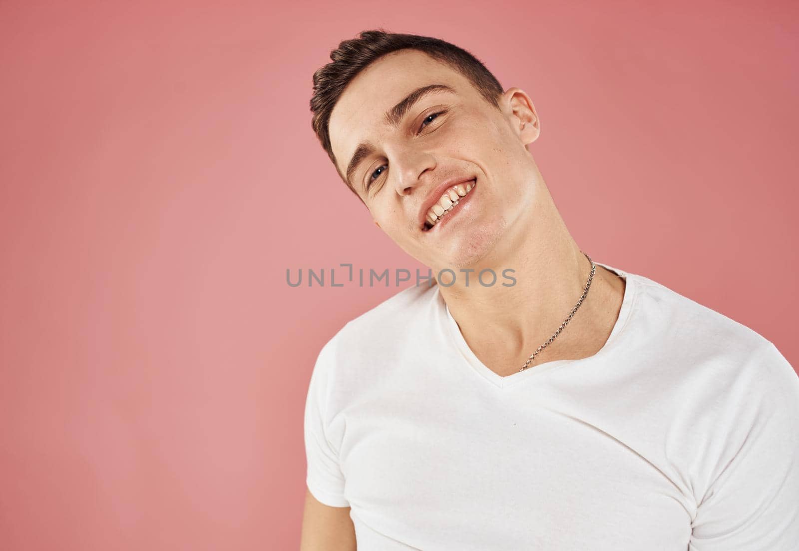 handsome man white t-shirt gesture with hands studio pink background. High quality photo