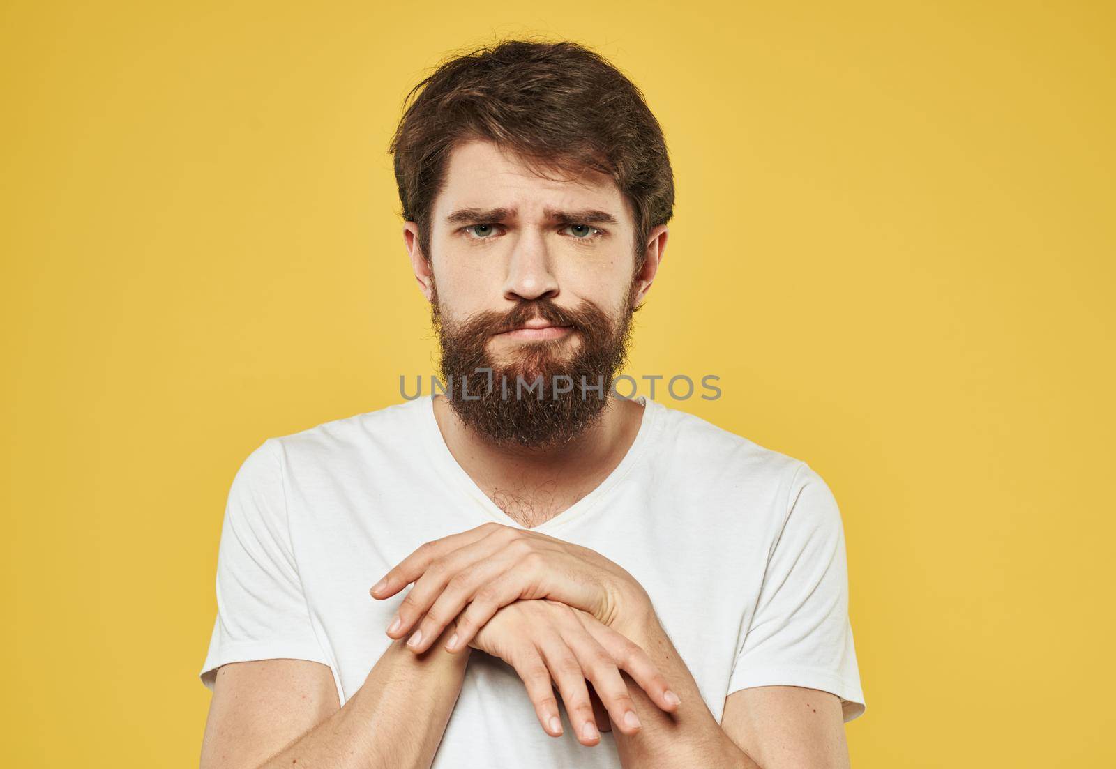 Emotional brunette man gestures with his hands on a yellow background. High quality photo