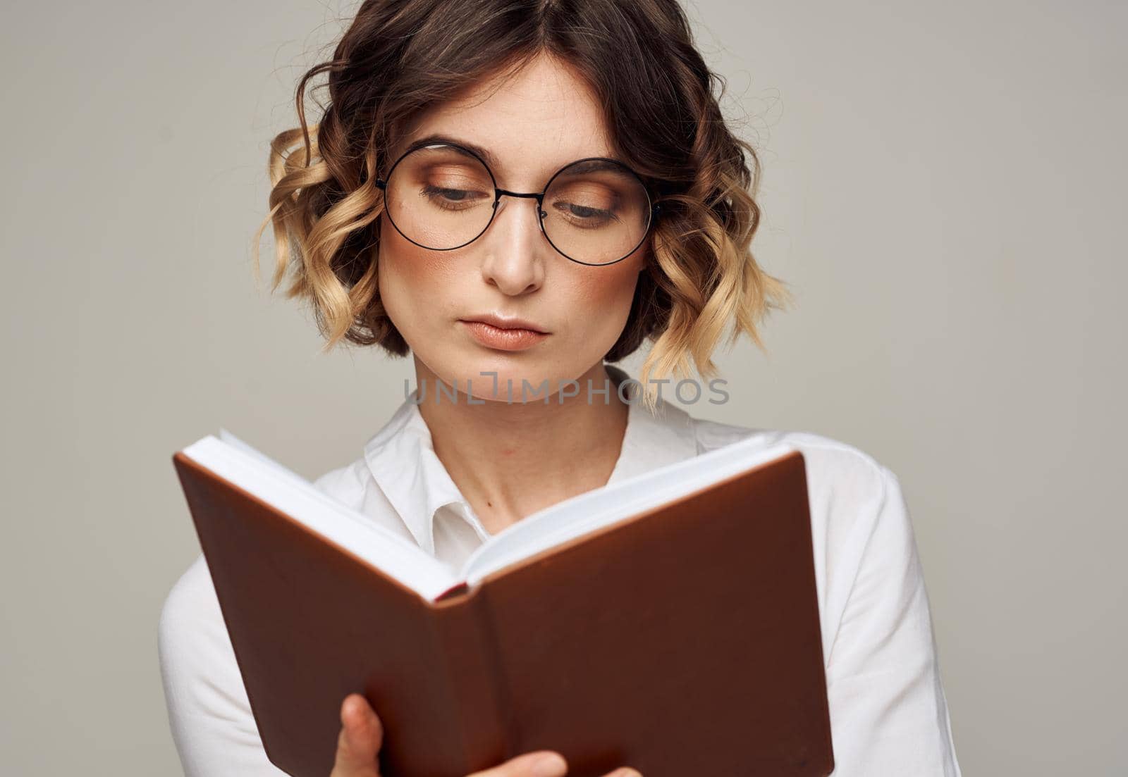 Woman with a notepad in her hands and wearing glasses on a gray background cropped view of a Light shirt. High quality photo