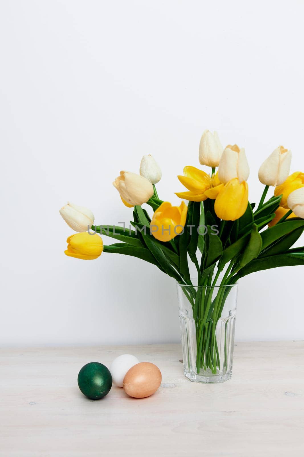 Easter eggs on the table and yellow tulips in a vase Copy Space by SHOTPRIME