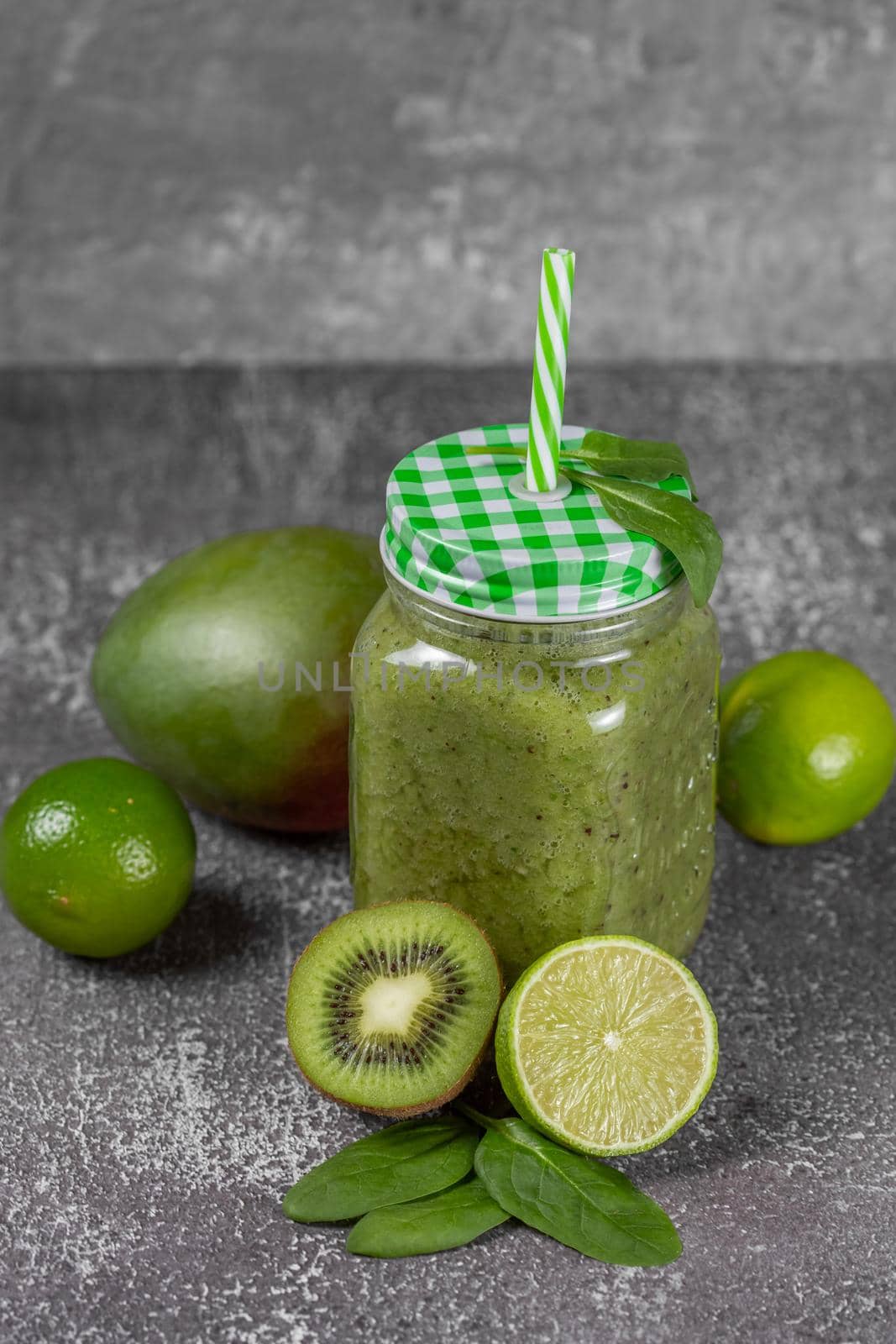 Diet and detox concept. Green smoothie with spinach, banana, kiwi and apple juice over dark background. Clean eating and healthy food.