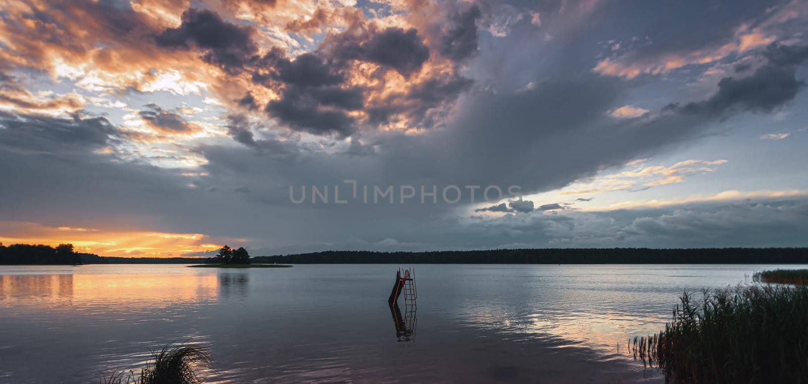 Grass and lake during sunset. Sunset on the lake. Beautiful natural landscape