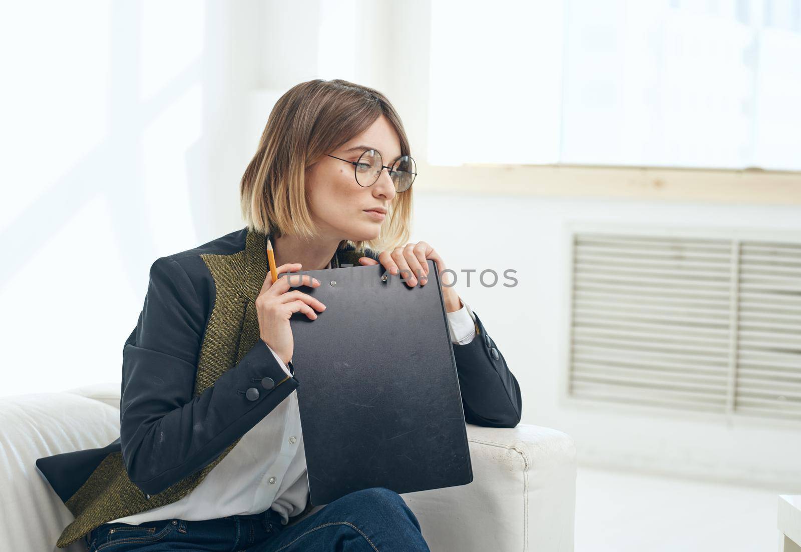 Business woman with a folder of documents and in a classic suit indoors near the window. High quality photo