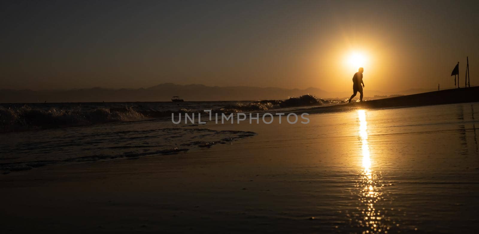 Silhouette of a man by the sea. Beautiful blazing sunset sea landscape. Amazing summer sunset view on the beach. 