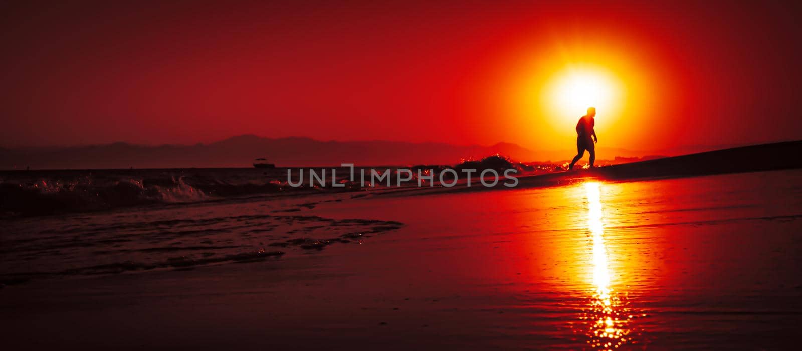 Silhouette of a man by the sea. Beautiful blazing sunset sea landscape. Amazing summer sunset view on the beach. 