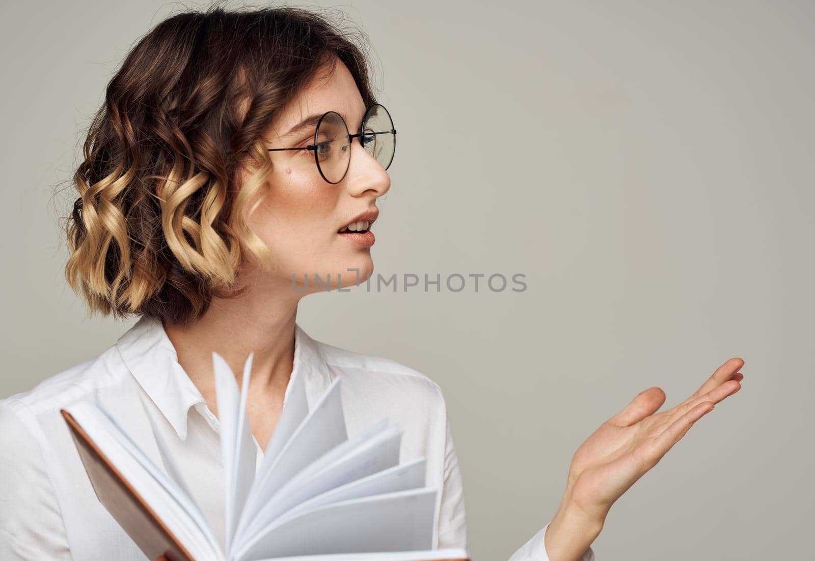 Emotional woman gestures with her hands on a gray background glasses on her face for hairstyle education. High quality photo