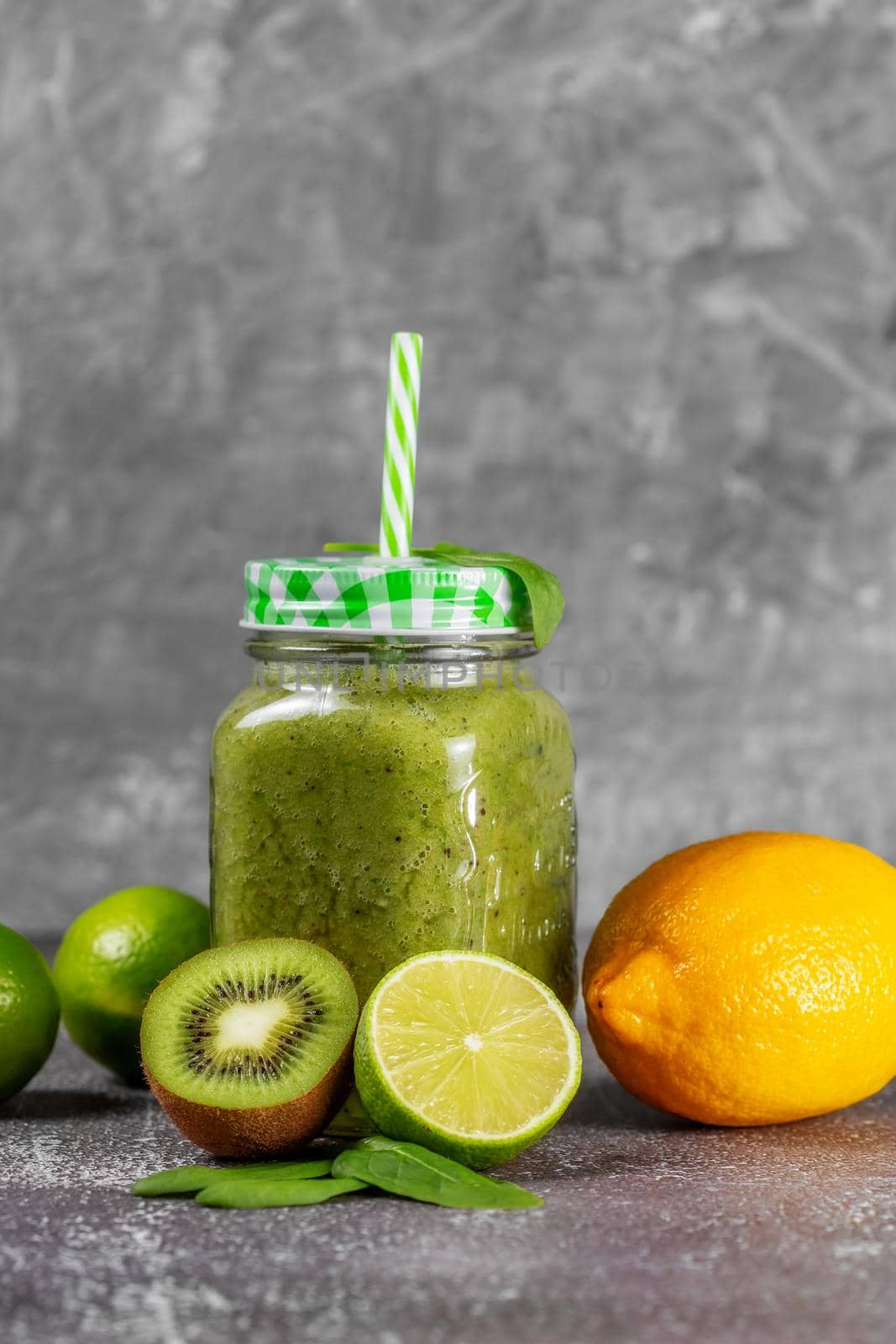 Freshly made kiwi lime and spinach smoothie on a gray concrete background. by galinasharapova