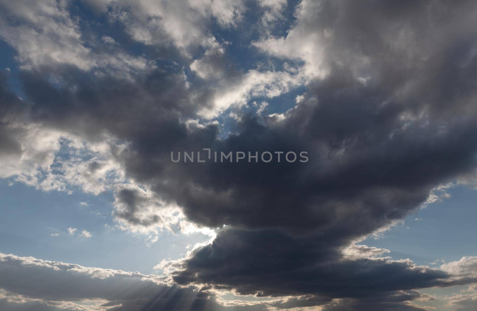 Sun rays shining through dark rainy clouds sky