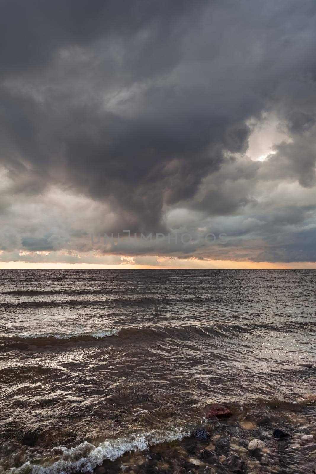 Amazing dramatic landscape. Dramatic dark clouds during sunset at sea. Dark sea water and heavy beautiful grey clouds.