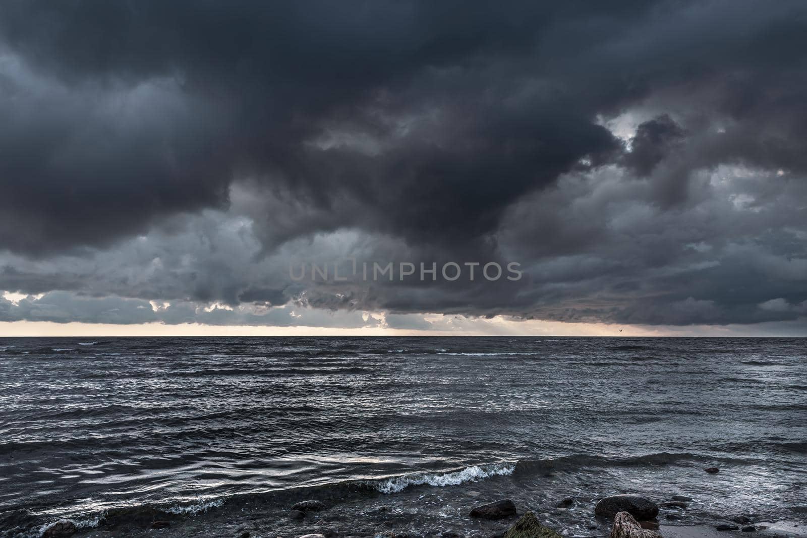 Amazing dramatic landscape. Dramatic dark clouds during sunset at sea. Dark sea water and heavy beautiful grey clouds.