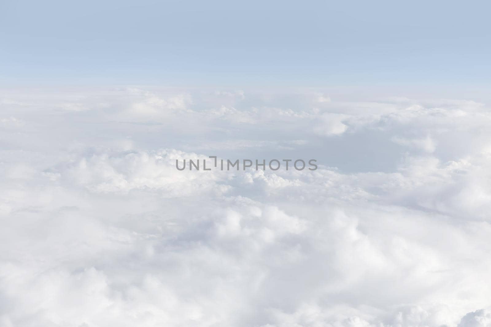 Sky with clouds, a view from an aeroplane above the clouds. Abstract nature background with clouds in light tonality. White cumulus clouds