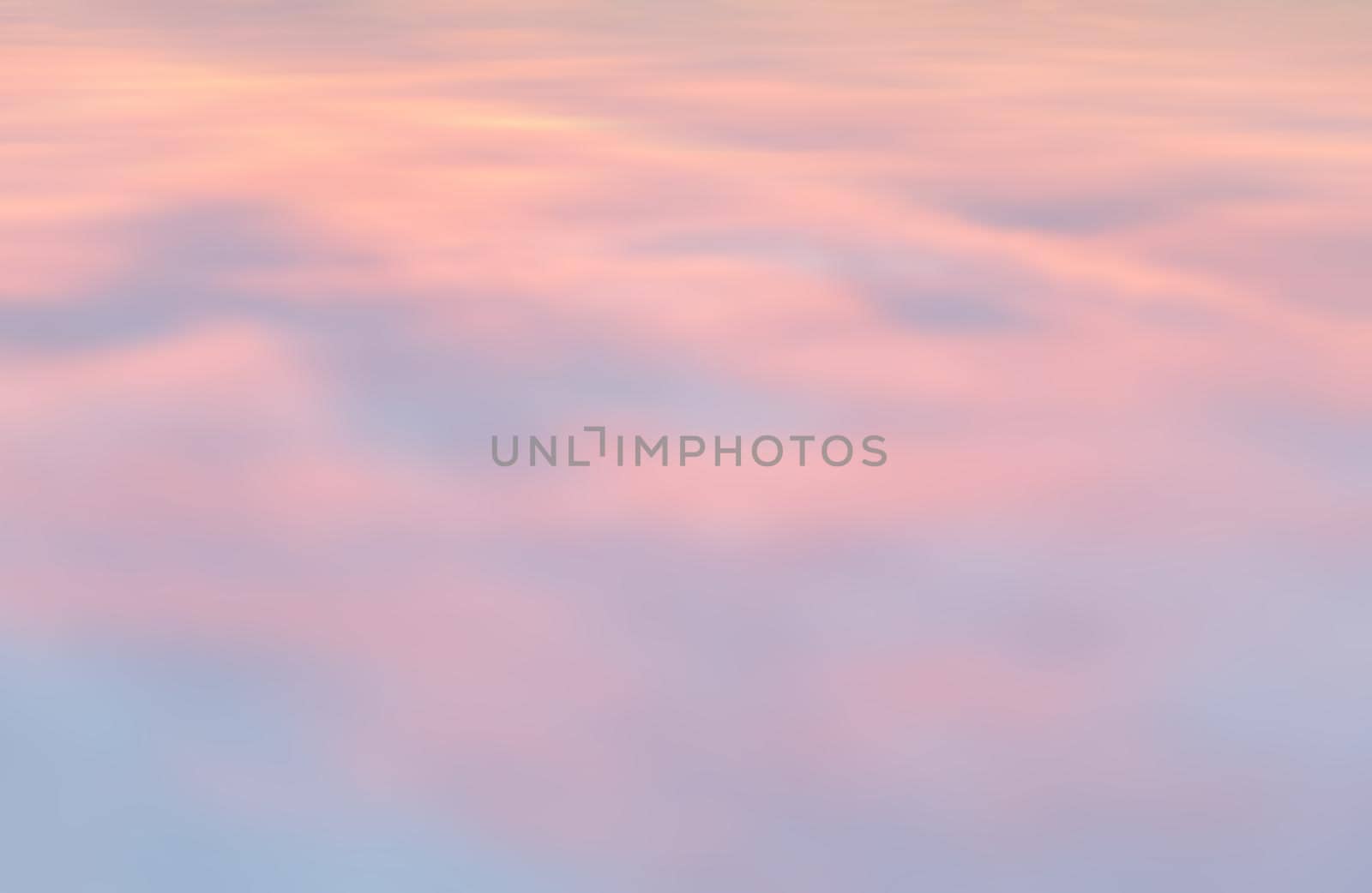 Blurry shot of the sunset sky. Abstract nature background with clouds in light tonality. 