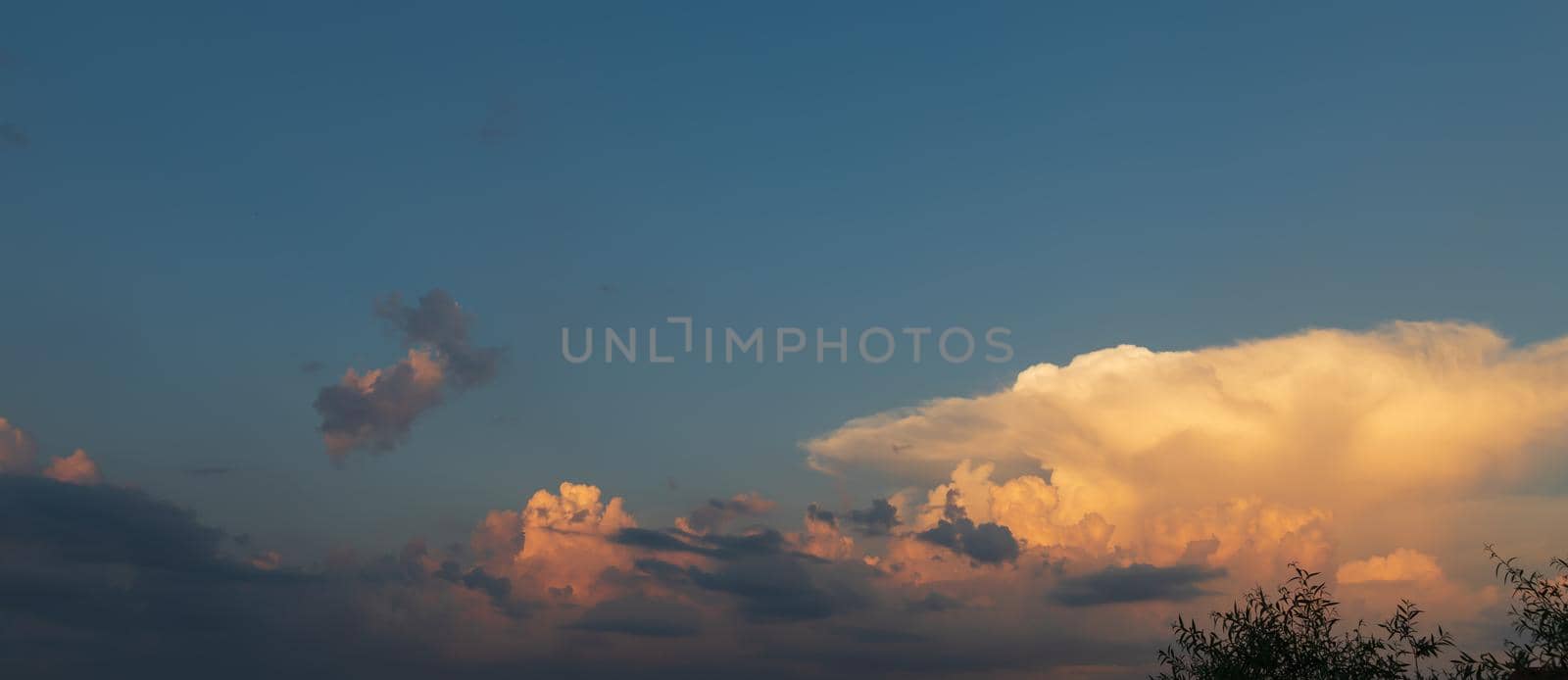 Sunset and clouds background. Sunset sky with fluffy clouds. Dramatic light at sunset