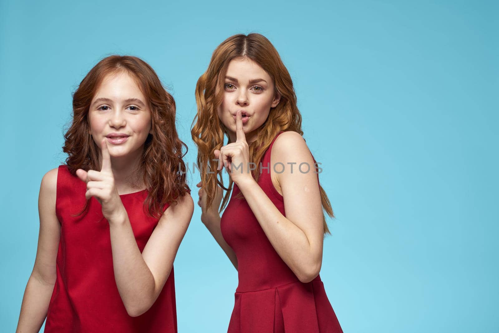 Mom and daughter red dress fun family blue background. High quality photo