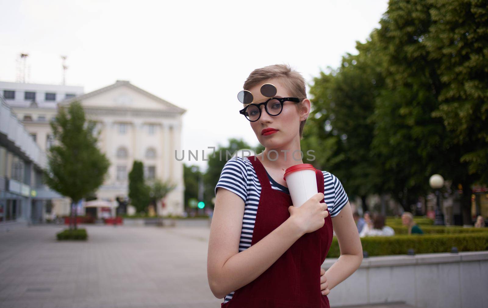 fashionable woman in a sundress and glasses on her face street nature summer trees building. High quality photo