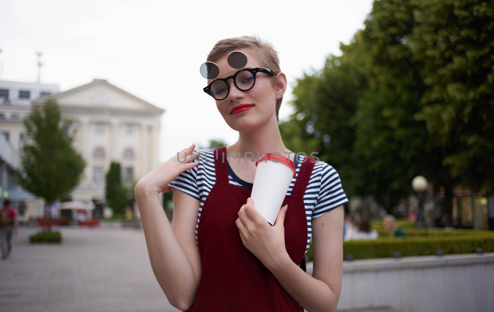 fashionable woman in a sundress and glasses on her face street nature summer trees building. High quality photo