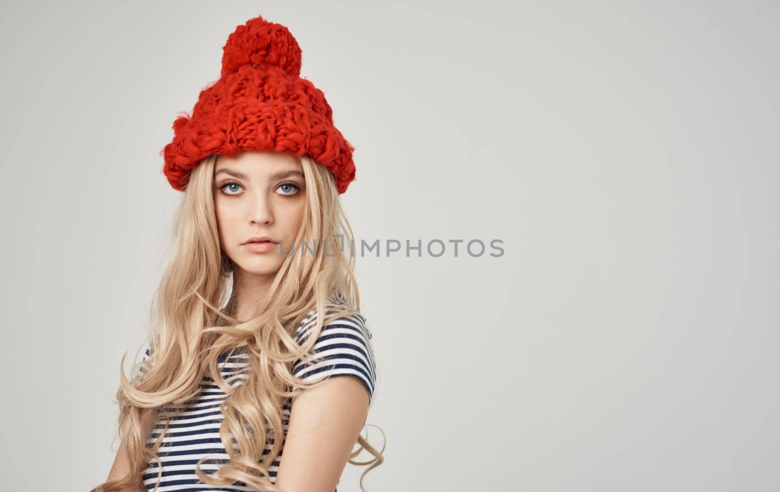 emotional blonde woman in striped t-shirt with cap on her head on phone cropped view. High quality photo