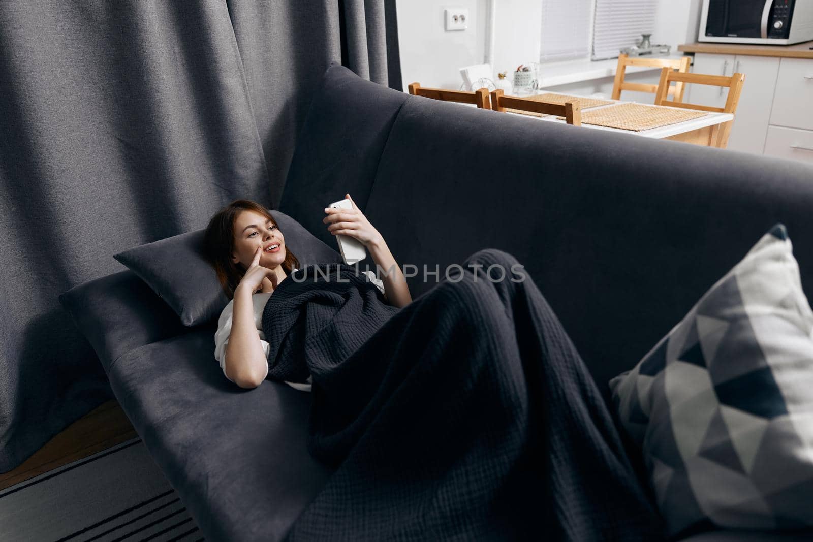 woman with phone in hand resting lying on the couch top view. High quality photo