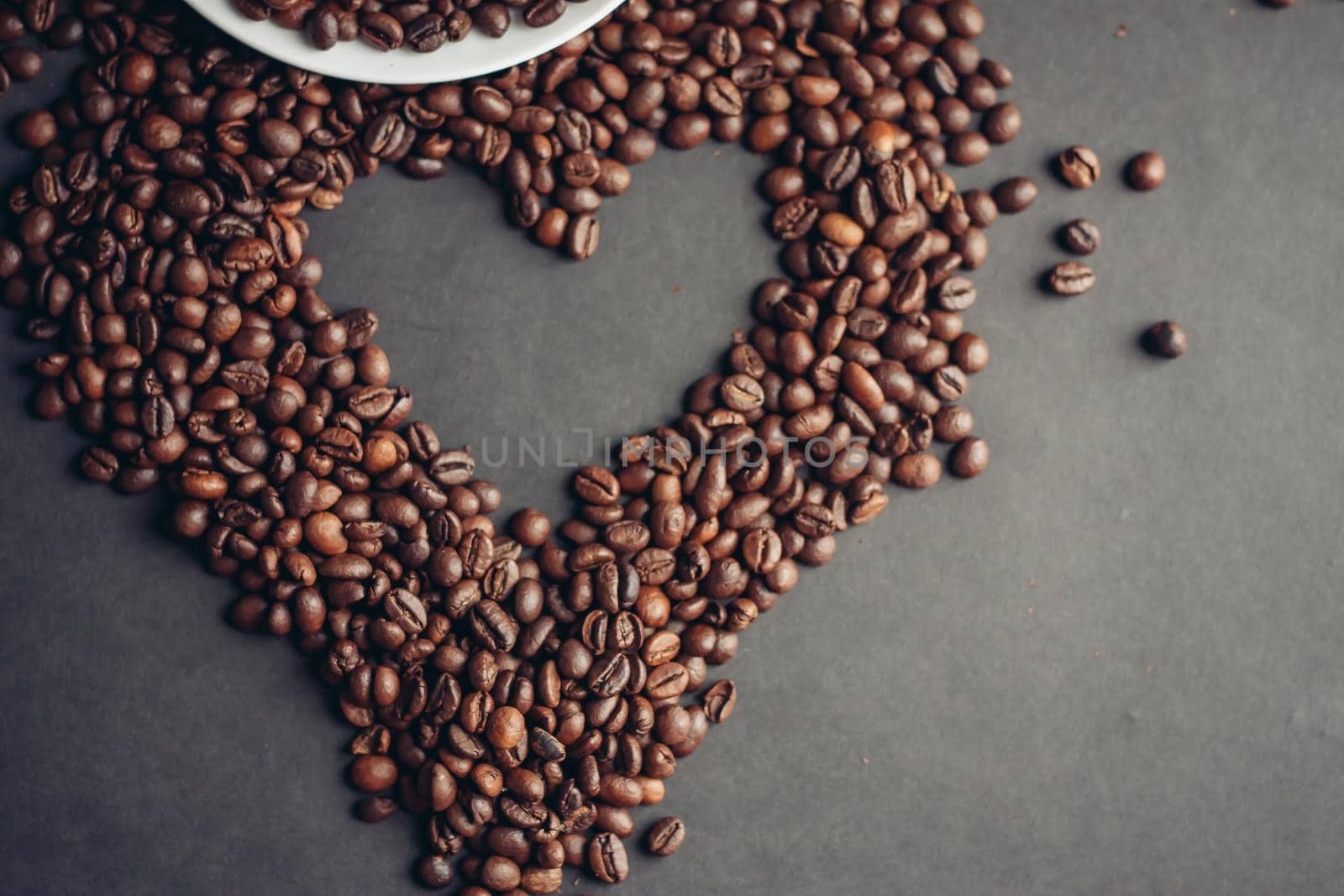 coffee beans on a gray background and a hot aromatic drink on a saucer top view. High quality photo