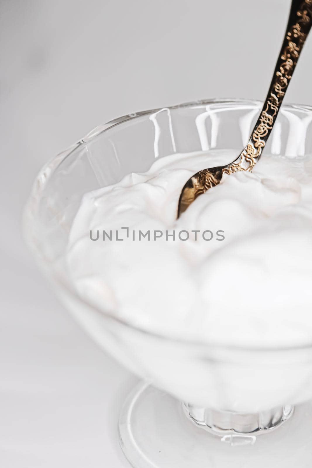 White whipped dessert cream served in a glass bowl, creamy texture closeup