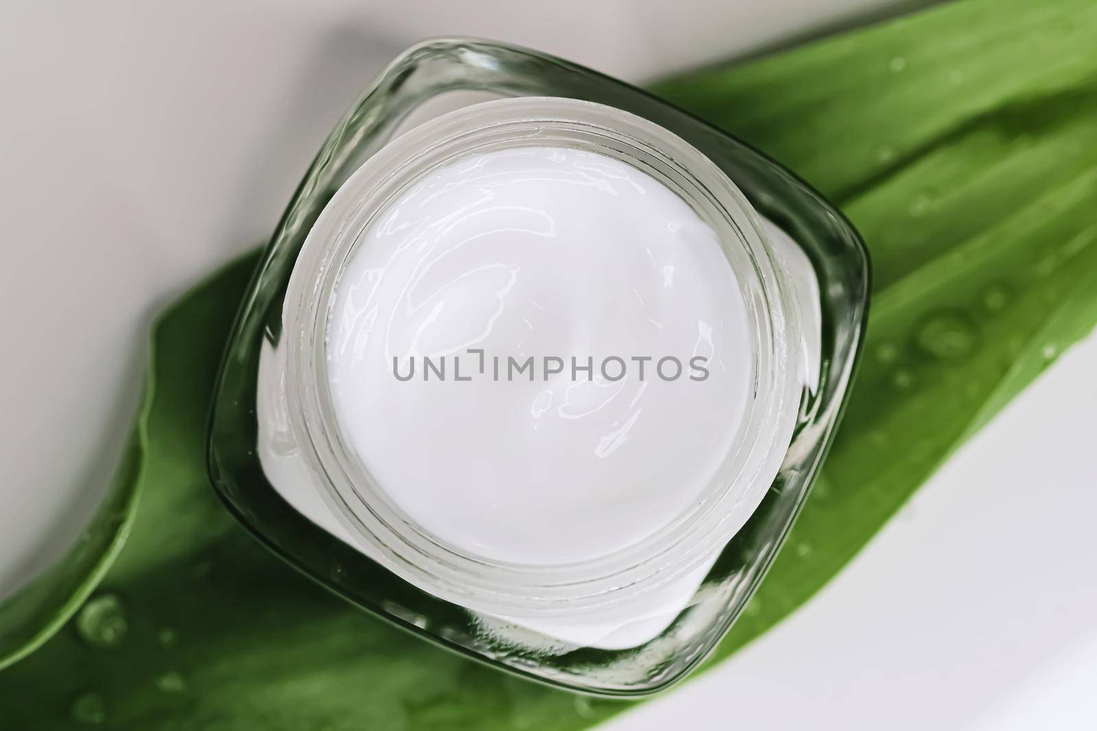 Natural moisturising cream jar on green leaves as beauty flatlay, spa cosmetics and skincare by Anneleven