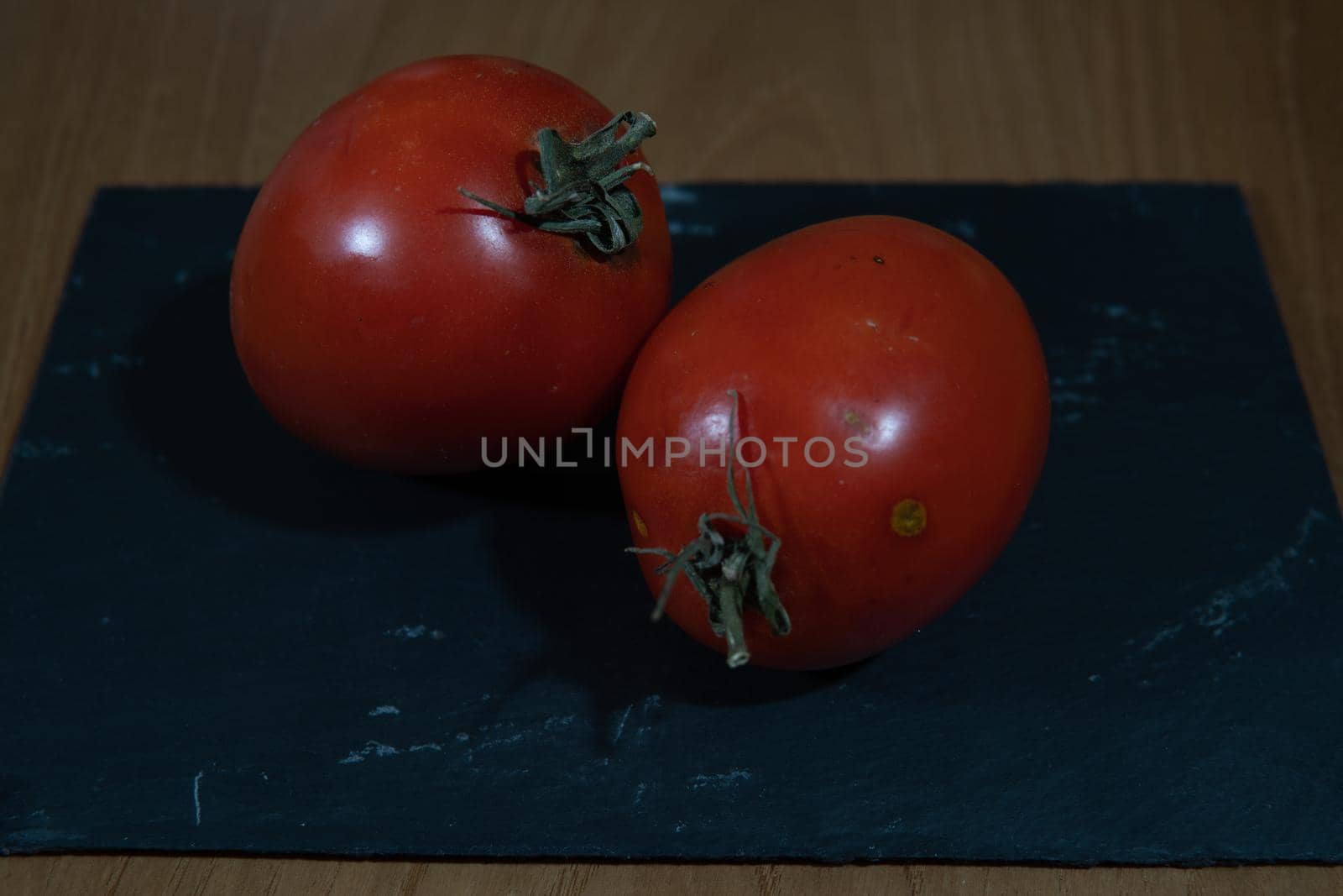 Natural red tomatoes on a black slate and wood background by xavier_photo