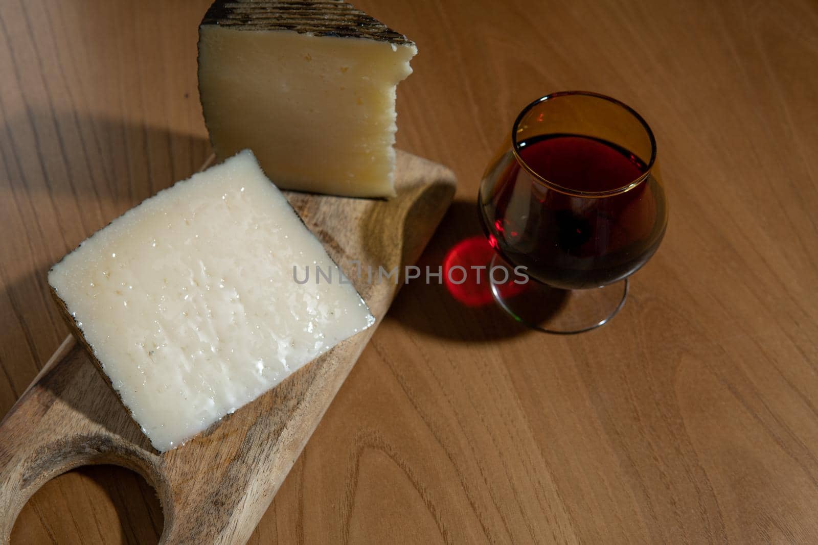 Cheese wedges on wooden board and red wine