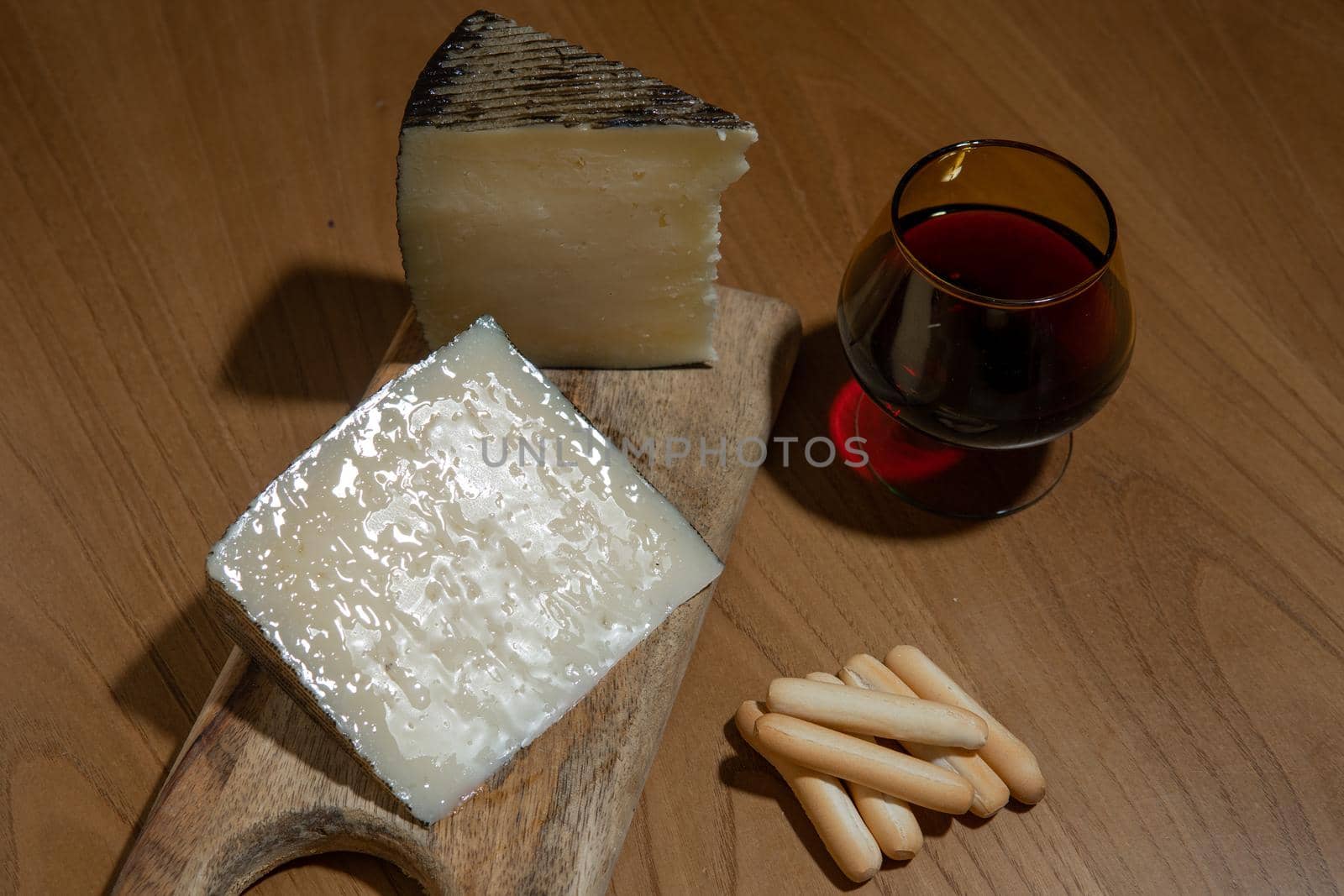 Cheese wedges on wooden board and red wine