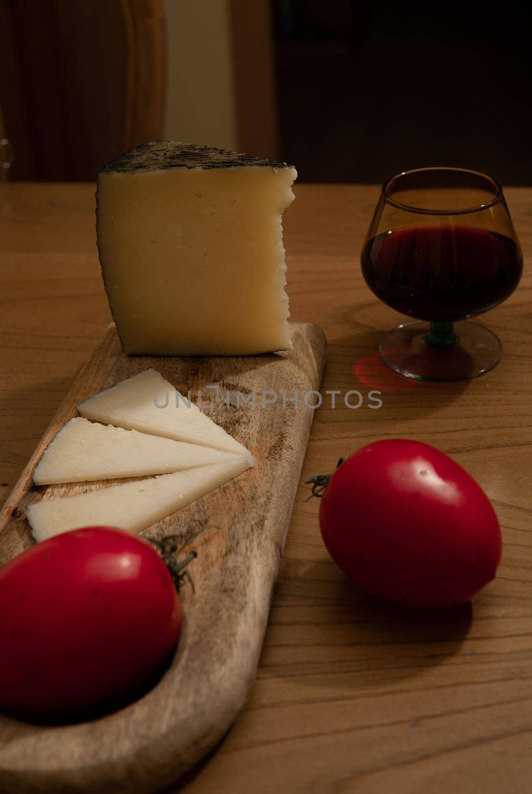 Cheese wedge with tomato, bread sticks and red wine