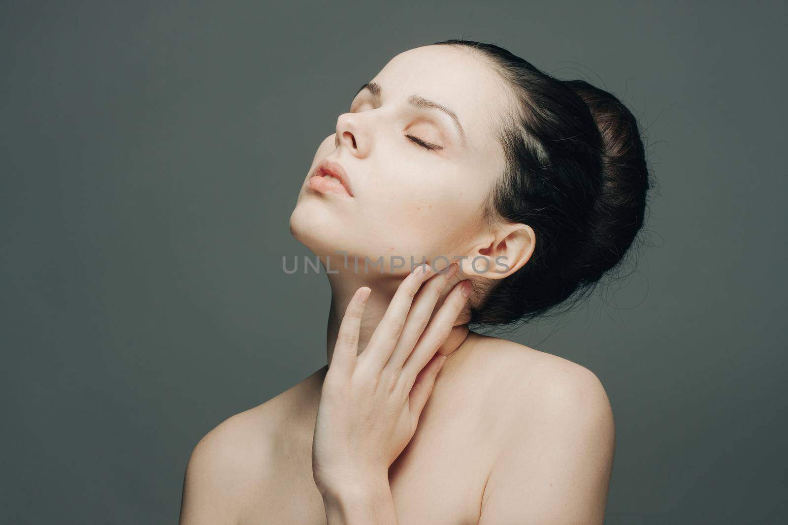 pretty brunette with bare shoulders gathered hair hand near face. High quality photo