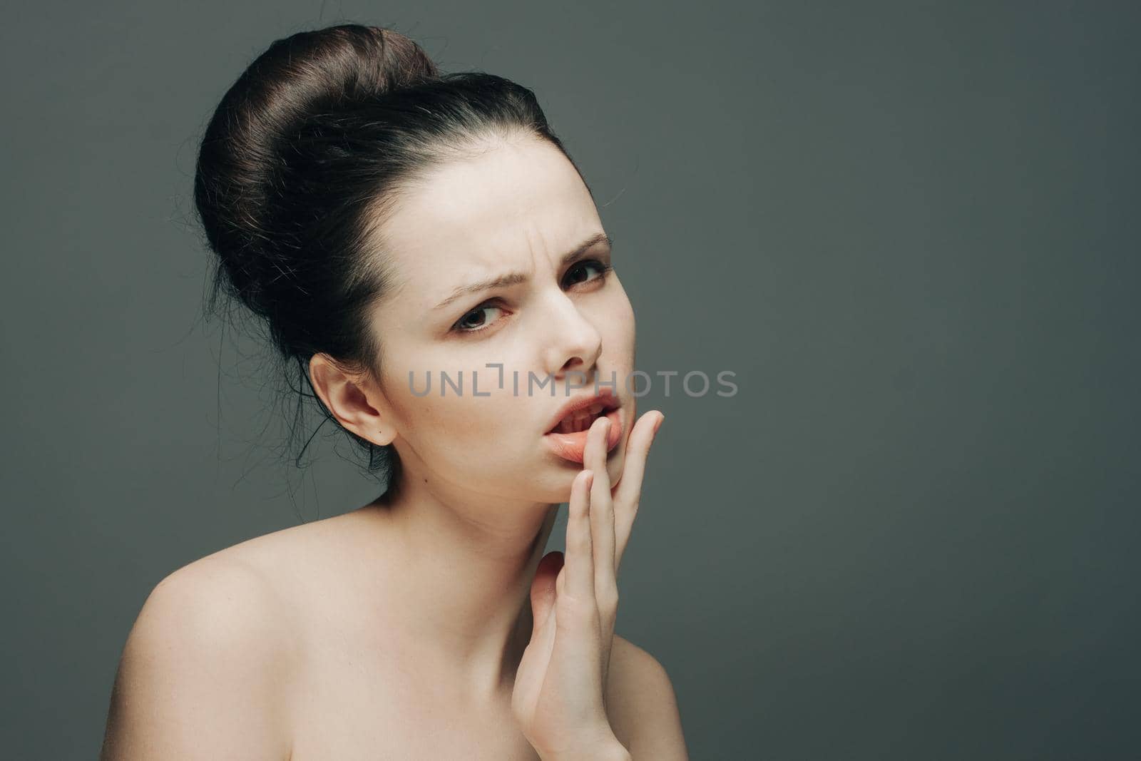 brunette with bare shoulders emotions glamor hand near face. High quality photo
