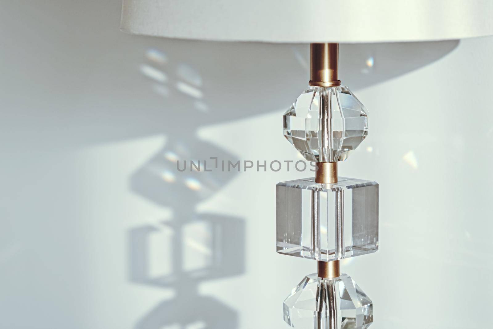 Gold and crystal details of a bedside lamp with shadows at sunset, luxury home decor closeup