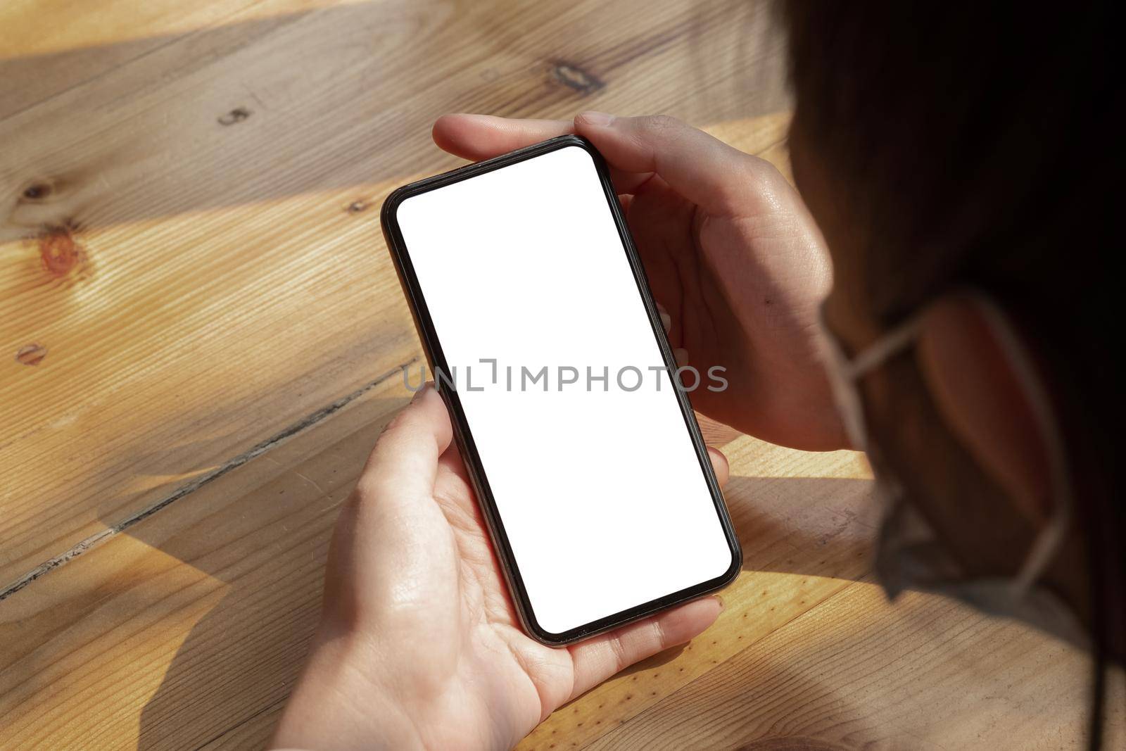 Top view woman wear mask holding mobile phone with blank white screen at cafe.