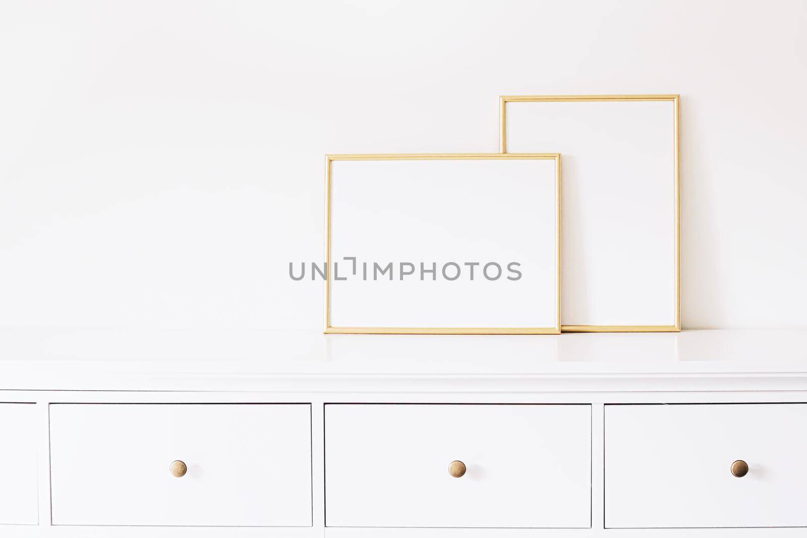 Two golden vertical and horizontal frames on white furniture, luxury home decor and design for mockup creations