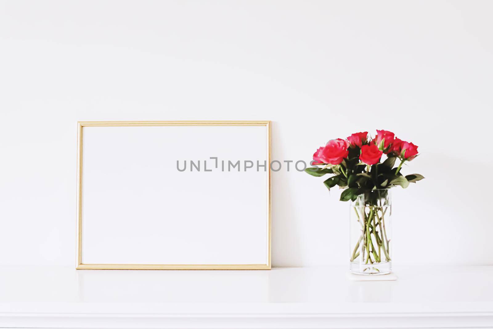 Golden horizontal frame and bouquet of rose flowers on white furniture, luxury home decor and design for mockup creations